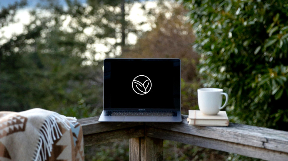 A laptop standing on a railing next to a cup of coffee